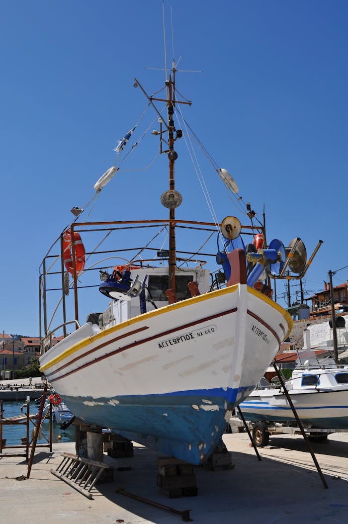 A vibrant fishing boat docked under a bright blue sky in a harbor, offering nautical charm.